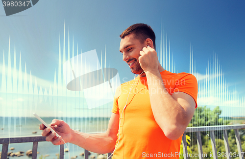 Image of smiling young man with smartphone and earphones