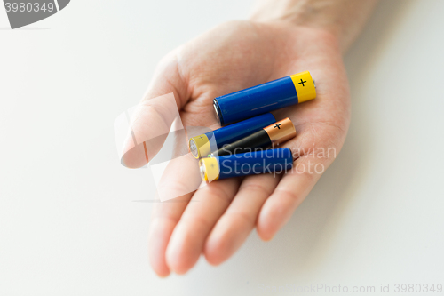 Image of close up of hands holding alkaline batteries heap