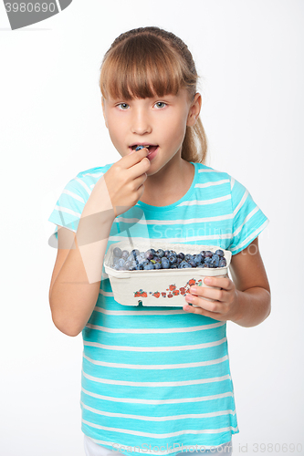 Image of Little girl holding a box with bilberries and eating it