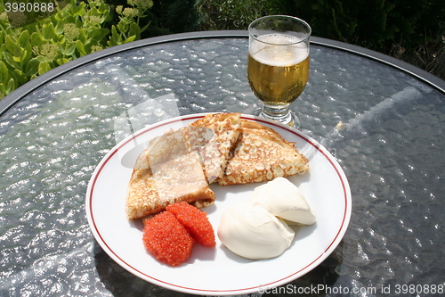 Image of Crepes, caviar, creme fraiche and a glass of cold beer