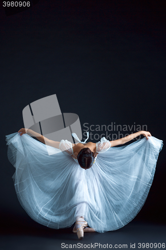 Image of Portrait of the classical ballerina in white dress on black background