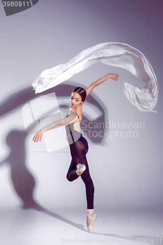 Image of Ballerina in black outfit posing on toes, studio background.