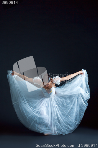 Image of Portrait of the classical ballerina in white dress on black background
