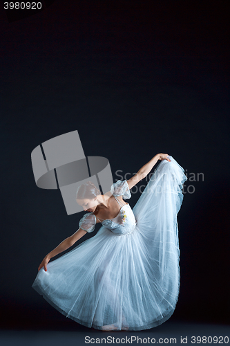 Image of Portrait of the classical ballerina in white dress on black background