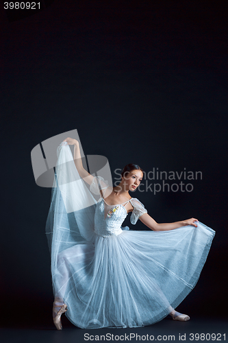 Image of Portrait of the classical ballerina in white dress on black background