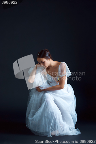 Image of Portrait of the classical ballerina in white dress on black background