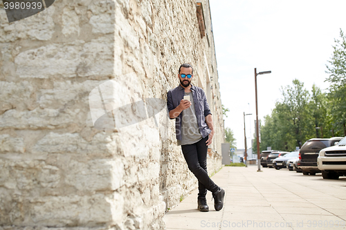 Image of man texting message with smartphone on city street