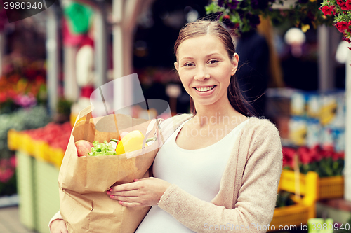 Image of pregnant woman with bag of food at street market