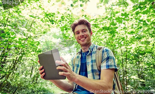 Image of happy man with backpack and tablet pc in woods