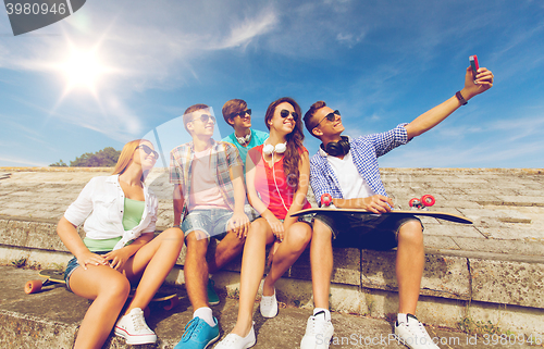 Image of group of smiling friends with smartphone outdoors