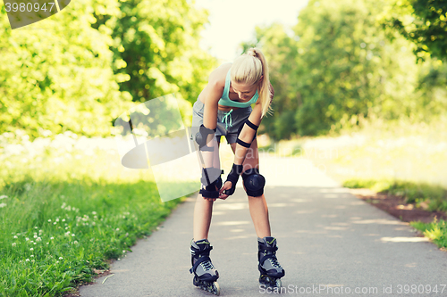 Image of happy young woman in rollerskates riding outdoors