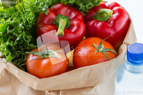 Image of close up of paper bag with vegetables and water