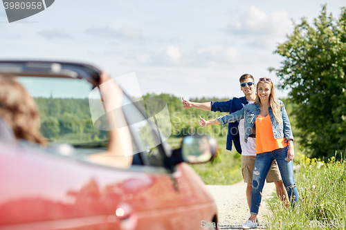 Image of couple hitchhiking and stopping car on countryside