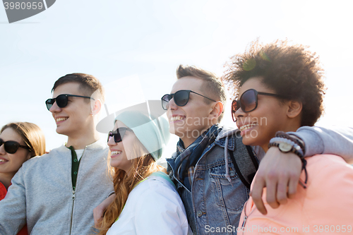 Image of happy teenage friends in shades hugging outdoors