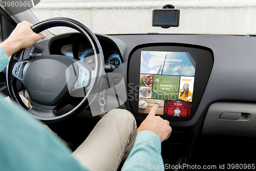 Image of man driving car with news on board computer