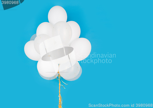 Image of close up of white helium balloons over blue