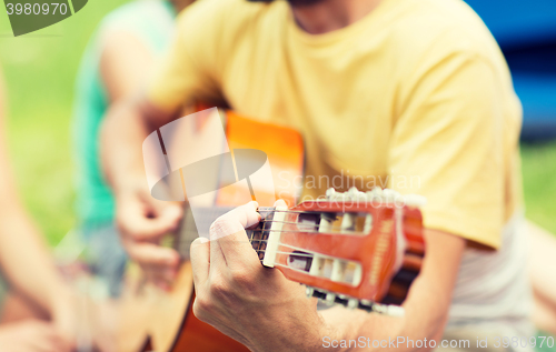 Image of close up of man playing guitar at camping