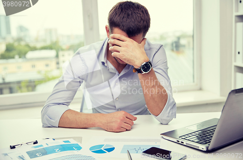 Image of stressed businessman with papers in office