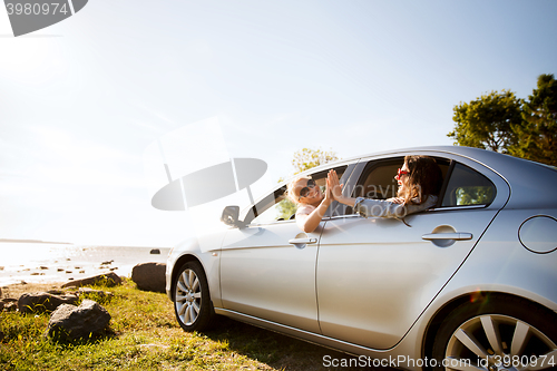 Image of happy teenage girls or women in car at seaside