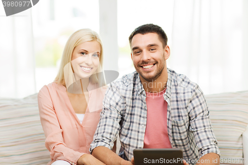 Image of smiling happy couple with tablet pc at home