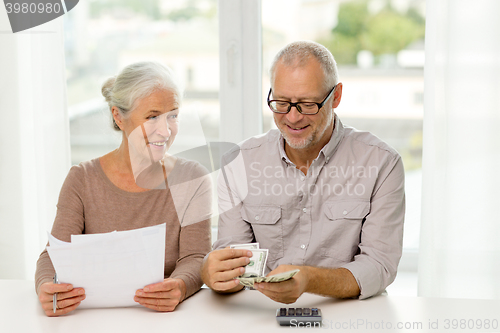 Image of senior couple with money and calculator at home
