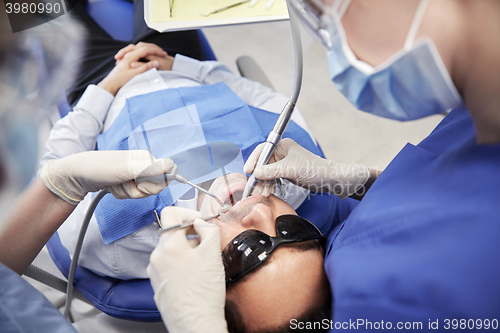 Image of female dentist treating male patient teeth