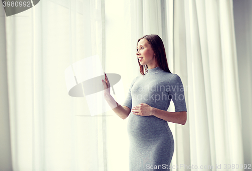 Image of happy pregnant woman with big tummy at home