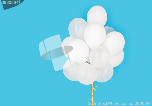 Image of close up of white helium balloons over blue