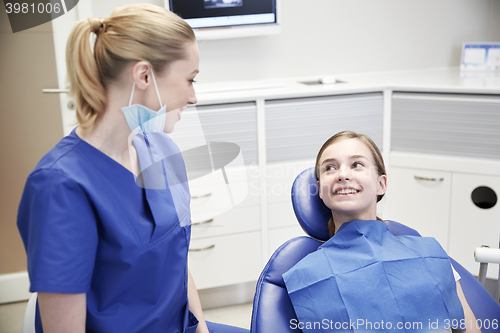 Image of happy female dentist with patient girl at clinic