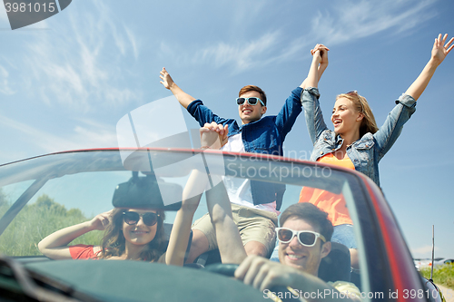 Image of happy friends driving in cabriolet car at country