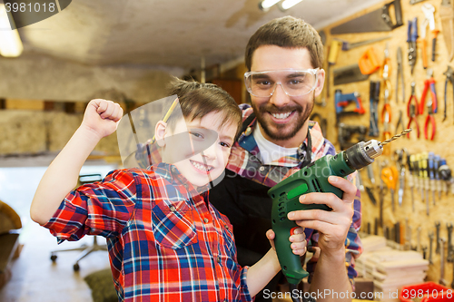 Image of father and son with drill working at workshop