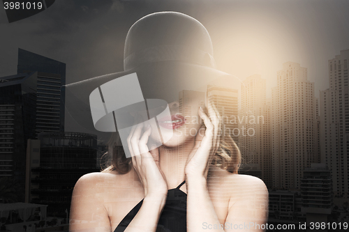 Image of beautiful woman in black hat over dark background