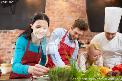 Image of happy friends and male chef cooking in kitchen
