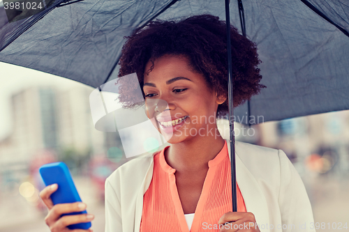 Image of businesswoman with umbrella texting on smartphone