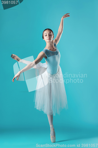 Image of Ballerina in white dress posing on toes, studio background.