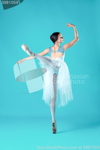 Image of Ballerina in white dress posing on toes, studio background.