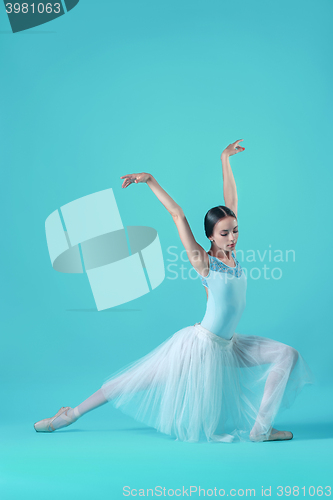 Image of Ballerina in white dress posing on toes, studio background.