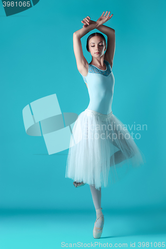 Image of Ballerina in white dress posing on toes, studio background.