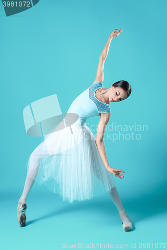 Image of Ballerina in white dress posing on toes, studio background.