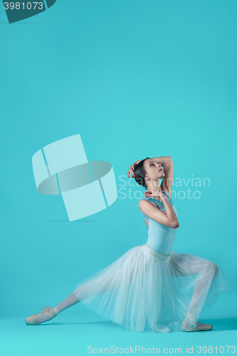 Image of Ballerina in white dress posing on toes, studio background.