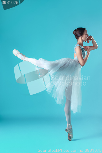 Image of Ballerina in white dress posing on toes, studio background.