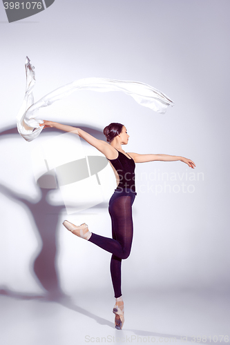 Image of Ballerina in black outfit posing on toes, studio background.