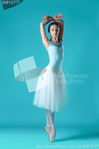 Image of Ballerina in white dress posing on toes, studio background.