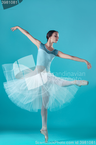 Image of Ballerina in white dress posing on toes, studio background.