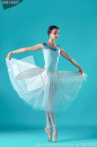 Image of Ballerina in white dress posing on toes, studio background.