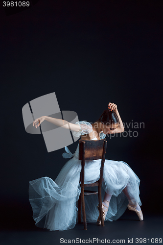 Image of Portrait of the classical ballerina in white dress on black background