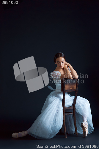 Image of Portrait of the classical ballerina in white dress on black background