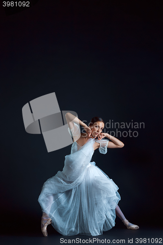 Image of Portrait of the classical ballerina in white dress on black background