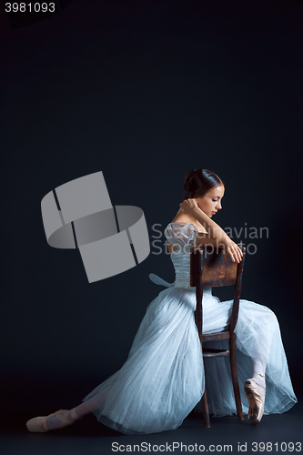Image of Portrait of the classical ballerina in white dress on black background