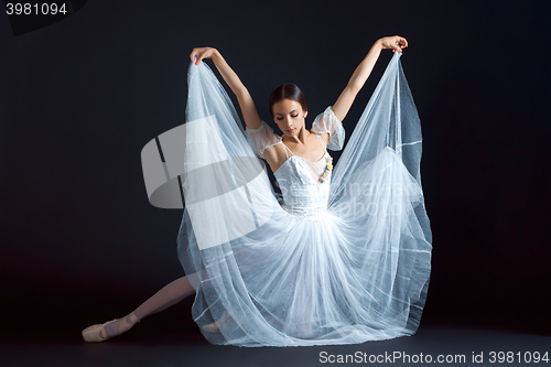 Image of Portrait of the classical ballerina in white dress on black background